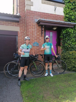 2 touring bicyclists in front of a house