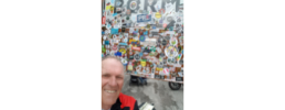 Man standing in front of street signed covered in travel stickers