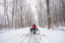 Man standing in front of bicycle on snow covered trail