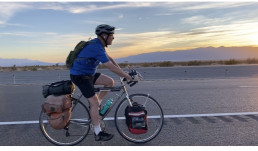 Man riding touring bicycle along roadside