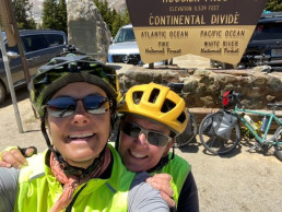 Two woman bicyclists posing in front of Continental Divide sign