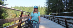 Woman posing next to bicycle on bridge