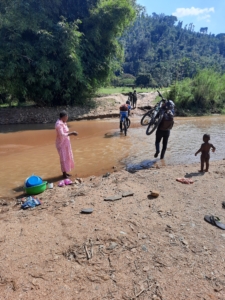 Cyclists carrying loaded bikes and crossing a small creek