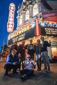 A group of friends posing in front of a movie theater marquee