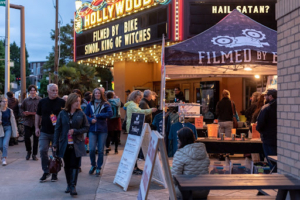 People standing on the sidewalk in front of a movie theater