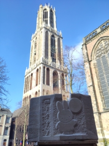 Stone sculpture in front of an old stone tower building