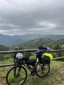 Loaded touring bicycle propped against a fence overlooking a mountain range