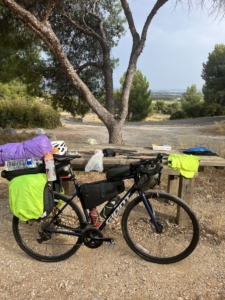 A loaded touring bicycle parked in front of a picnic table