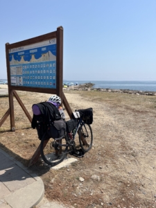 A bicycle leaning against an informational sign by the sea